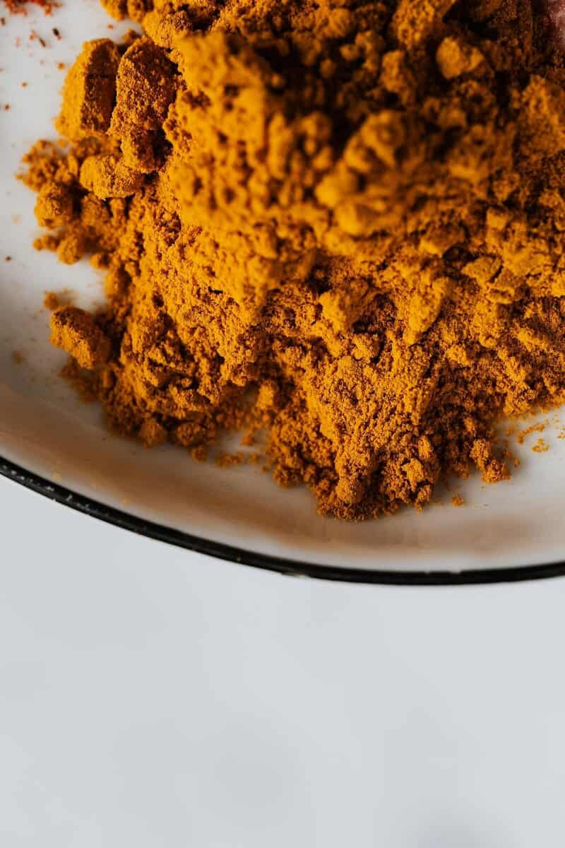 A vibrant close-up image of ground turmeric spice on a ceramic plate.